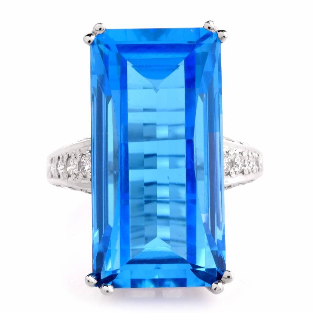 This stunning ring is centered with 1 genuine fancy baguette cut blue Topaz approx: 35.03cttw, double prong set and it is adorned with 28 genuine round brilliant cut Diamonds approx: 0.65cttw, G-H color, VS1 clarity, prong set. This exquisite ring