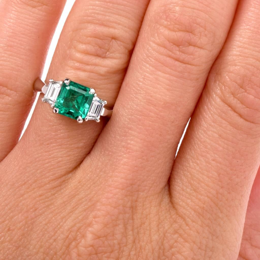This stunning three stone diamond ring of simple yet classically elegant design and feminine grace is crafted in solid platinum. It exposes a GIA certified 1.76 ct genuine Asscher-Cut colombian emerald of enchanting ‘intense green’ color, measuring
