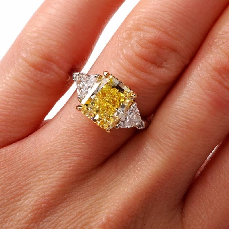 This exquisite Cartier diamond ring is crafted in solid platinum. Center displays a stunning rectangular brilliant cut natural fancy intense yellow diamond GIA certified approx. 4.33 carats with EVEN distribution and VS1 clarity it sides made of two