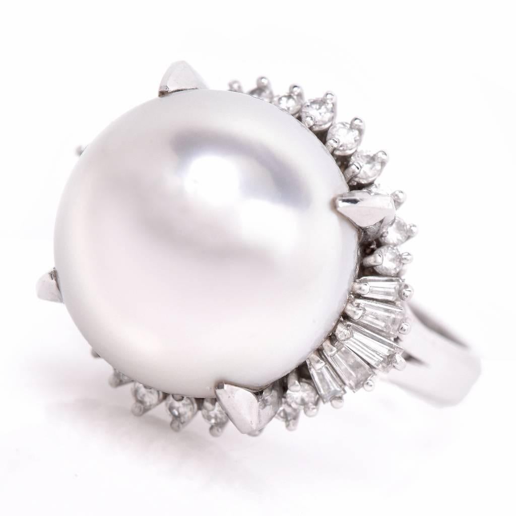 This exquisite cocktail ring with an outstanding, highly lustrous South Sea Pearl of an enchanting white with a subtle nuance of cream pink color set amidst a sparkling border of baguette and round-faceted diamonds is crafted in solid platinum and