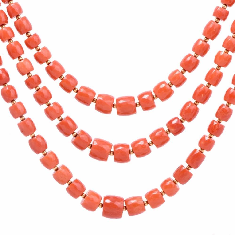 This elegant Vintage necklace incorporates three strands of graduated barrel-shaped natural red color coral beads measuring from 11mm to mm in diameter. The coral beads are silk-strung and inserted throughout the three strands by enchanting 18K