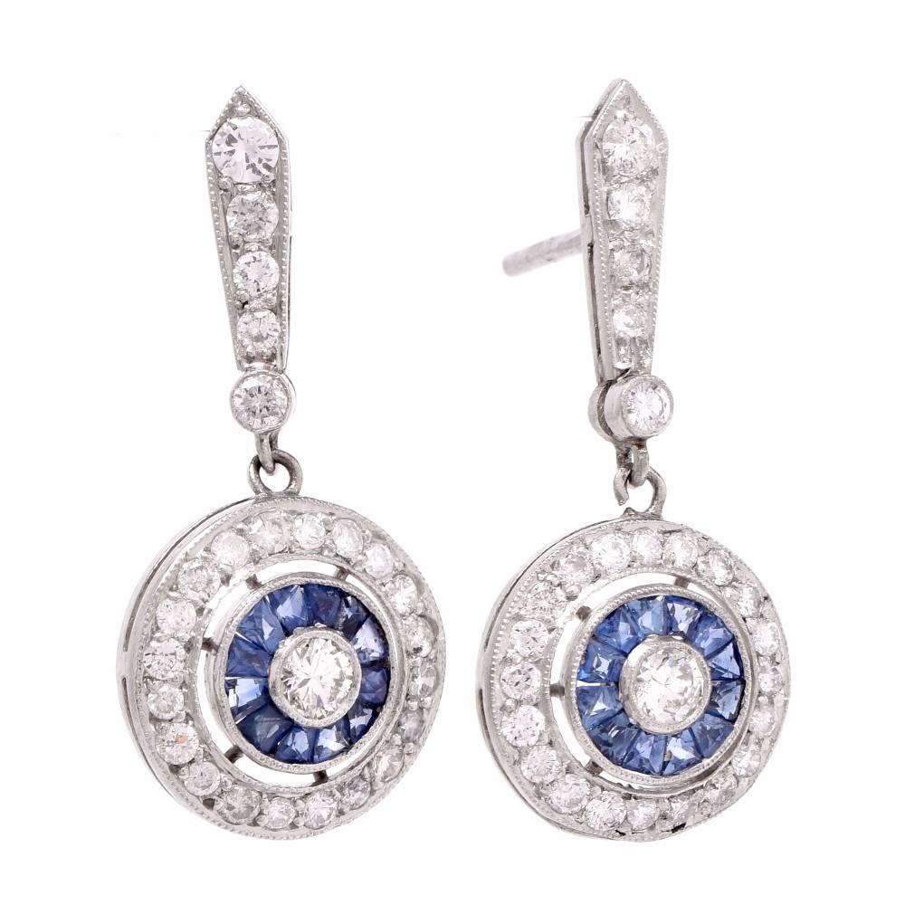 These vintage Art Deco design drop earrings of feminine grace and notable refinement are crafted in solid platinum. they centered with bezel-set round-faceted diamonds surrounded by channel-set french-cut blue sapphires approx. 0.35cts . This