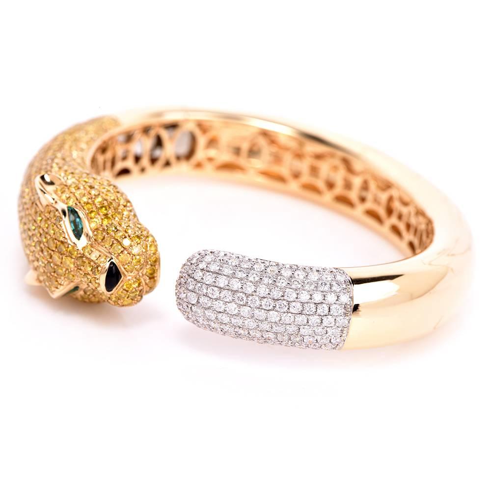 This impressive cuff bangle bracelet is crafted in polished 18K yellow gold, with a touch of 18K white gold applied to the colorless pave diamond settings. The bangle bracelet depicts the meticulously sculptured head of a panthere, swathed in 8.78