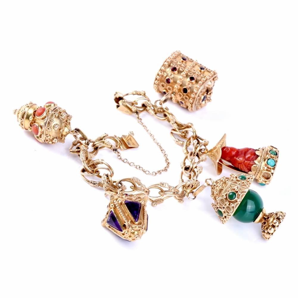 This Vintage Etruscan Revival style charm bracelet is crafted in solid 18K yellow gold a incorporates interlocking ovular links, embellished with Etruscan 'granulation' enhancements.  The bracelet suspends five  heavy charms consisting of a