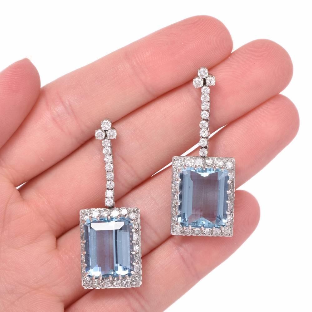 These fascinating vintage earrings from the Retro era are crafted in solid platinum.  They expose each an enchanting rectangular emerald-cut  aquamarine of Santa Maria quality, cumulatively weighing 21.50 carats. The translucent precious gemstones