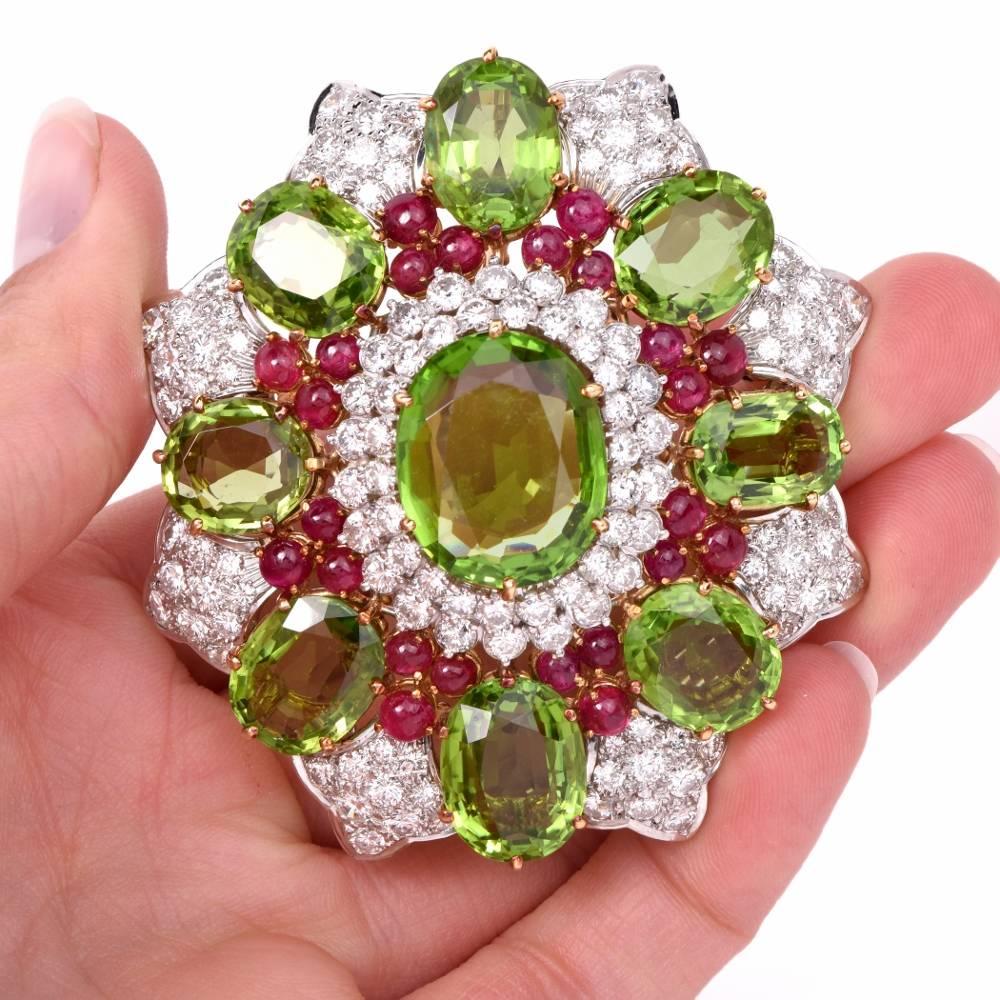 TThis vividly colored floral motif brooch is crafted in solid 18K white & yellow gold, weighing 63.3 grams. Creatively designed as a multi-layer oval plaque with gracefully scalloped perimeter, the brooch exposes at the center a prominent