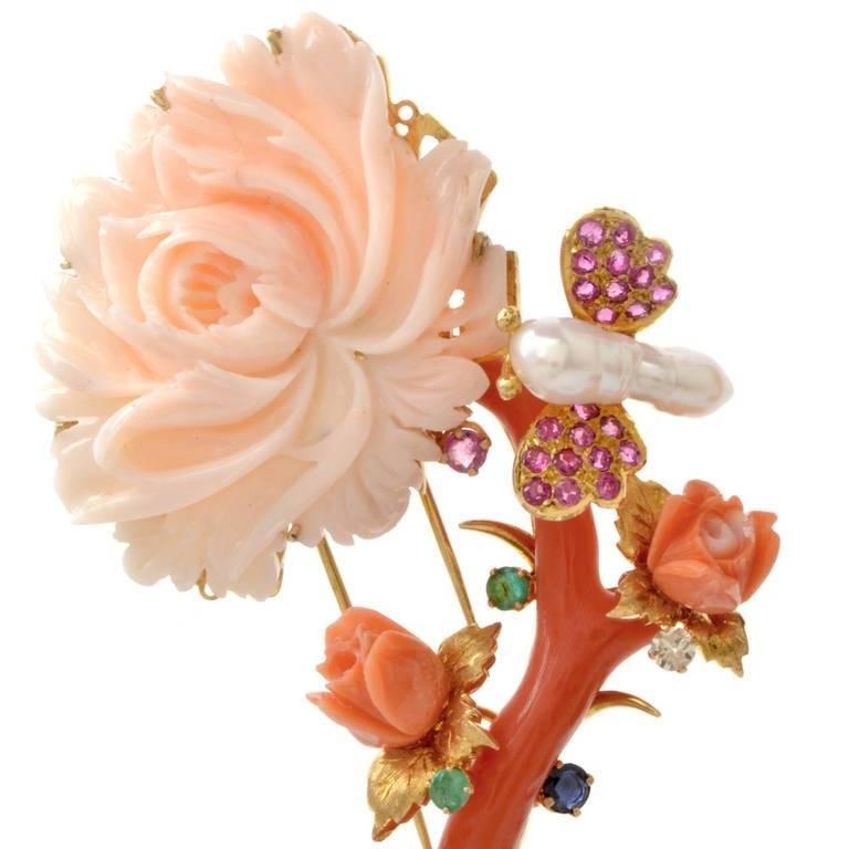 This authentic lapel brooch and pendant of artistic design and meticulous craftsmanship is crafted in solid 18K yellow gold, weighing approx. 42.4 grams. Designed as a naturalistically inspired flower on stem, with enchanting 'buds' in coral and