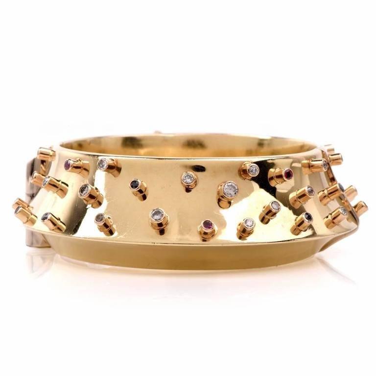 This one of a kind  bangle bracelet of interestig design with diamonds, sapphires and rubies is crafted in solid 14K yellow gold, weighing 71.4 grams and measuring 7.25 inches by  23 mm wide. The bracelet is  designed by David Stern, adorned 29