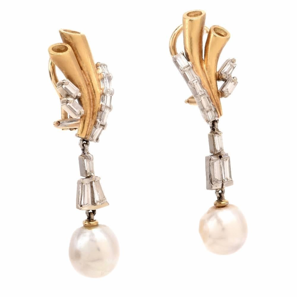 These stunning Vintage pendant earrings of alluring aesthetic are crafted in a combination of 18-karat white and yellow gold, incorporating each a lustrous off white pearl surmounted by tapered baguette diamonds suspending from a two-tone gold