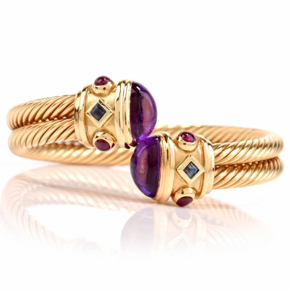 This high quality made Italian cuff bracelet is constructed in twisted- wire in 18 karat yellow gold and exposes a pair of amethyst cabochons at its open ends. The bracelet incorporates two adjacent strands of patterned yellow gold adjoined by a