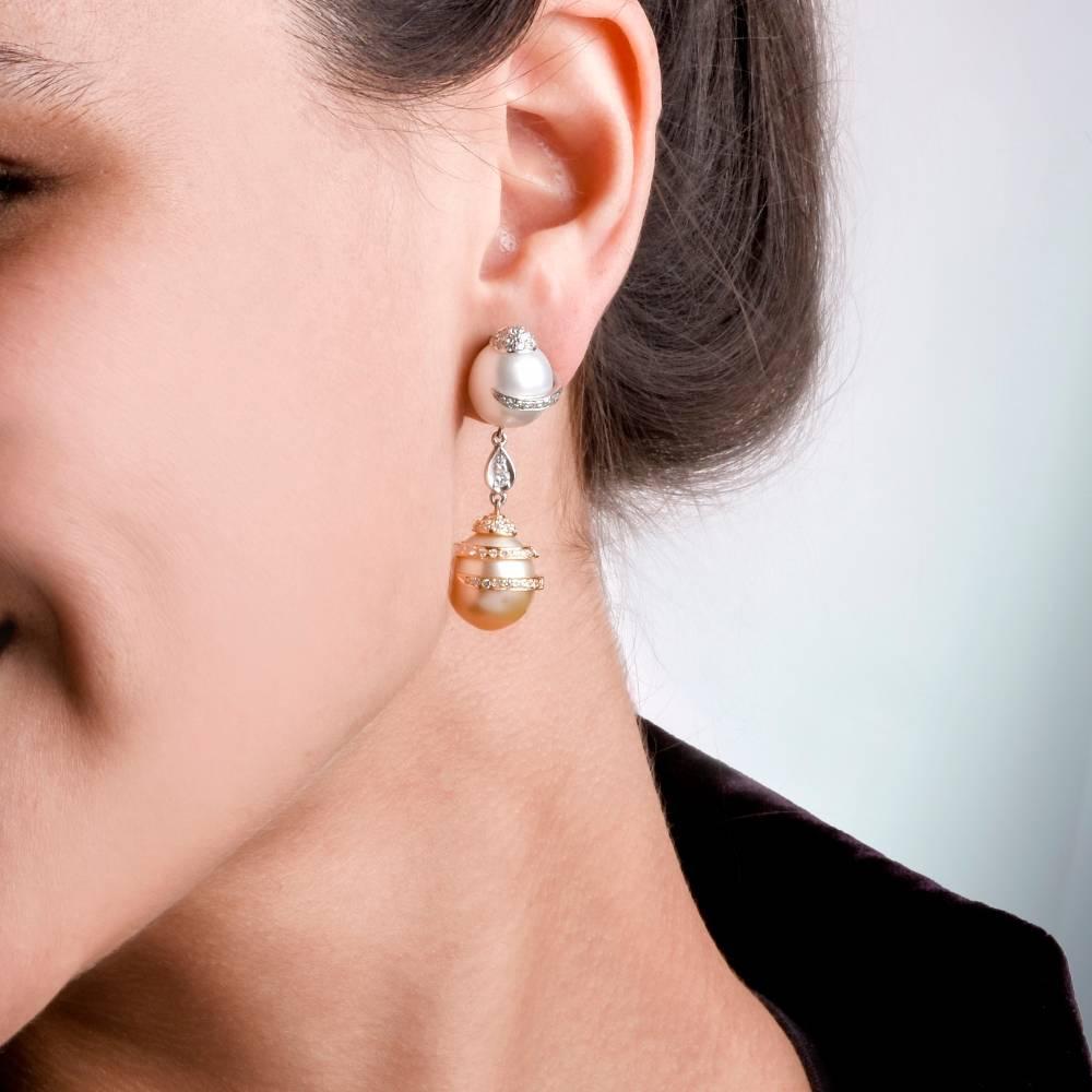 These Lovely estate pendant earrings with South Sea pearls and diamonds are crafted in a combination of 18 karat white and yellow gold. They incorporate a pair of south Sea golden pearls and a pair of South Sea silver gray pearls, capped and