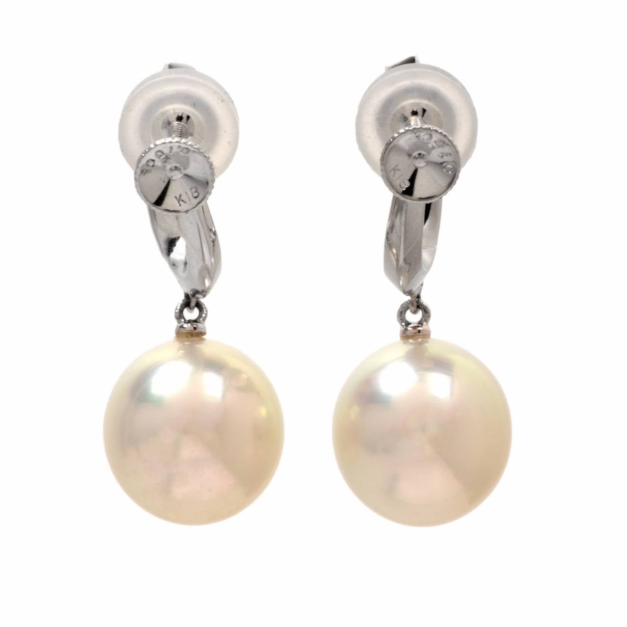 These gorgeous drop dangle earrings are crafted in solid 18K white gold. Sophisticated in every way, these earrings feature 16 genuine round cut dazzling diamonds approx: 0.35 cttw, G-H color, VS clarity, prong set and 2 genuine lustrous 11mm