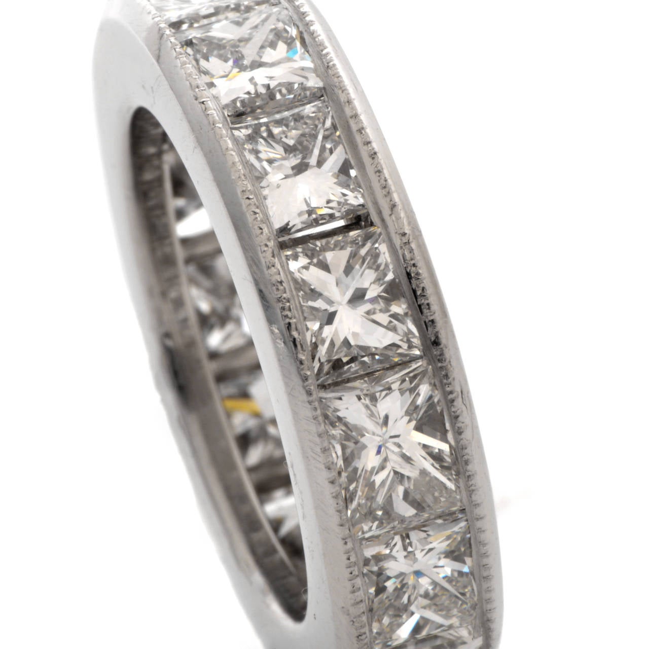 This captivating, tri-dimensional estate eternity band of sturdy construction and affluent  aesthetic  is crafted in  solid platinum and weighs approx. 12.2 grams. This estate eternity band  is resplendent in 15 sparkling, channel-set princess-cut