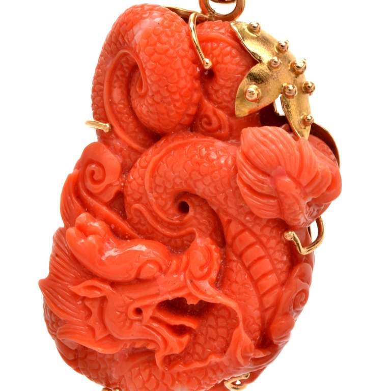 This vintage Italian genuine coral pendant, probably of European provenance, incorporates the immaculately sculptured curled body of a dragon mounted atop an 18k yellow gold frame. The natural organic gem of an enchanting 'salmon' red color is
