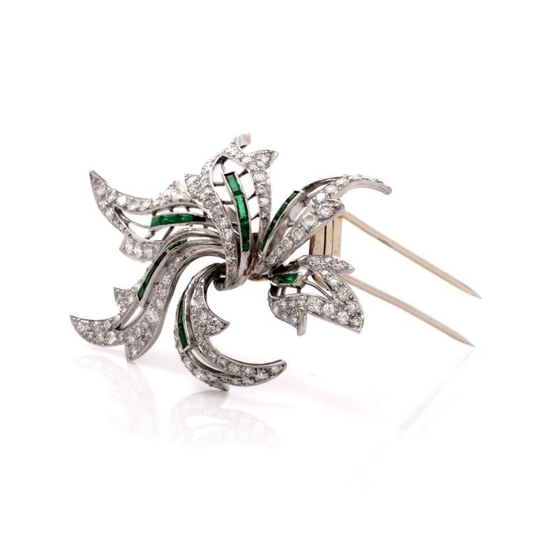 This antique  floral lapel brooch with diamonds and emeralds is crafted in solid platinum and weighs approx. 23.6 grams. Simulating an enchanting diamond flower with immaculately scalloped petals and emerald stems, this conspicuous Retro lapel