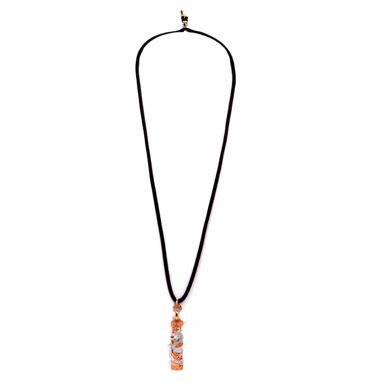 This elegant estate drop pendant necklace is crafted in solid 18K rose gold. Showcasing  a lovely and stylish black rope chain necklace that is centered with a cylinder shaped pendant. The pendant is centered with a detailed carving of a dragon that