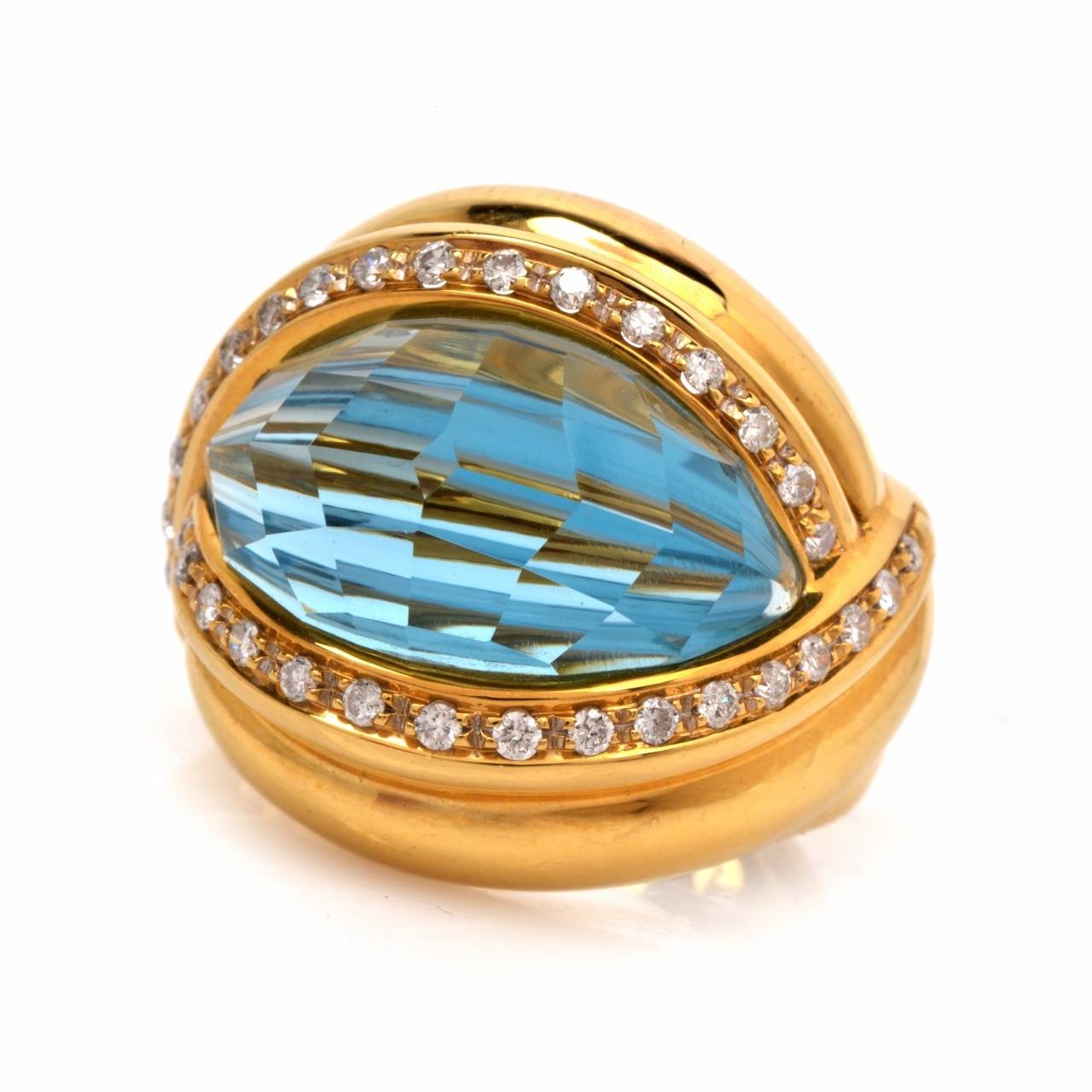 This estate Italian made cocktail ring crafted in solid 18K yellow gold weighs 15.5 grams.  Designed as an impressive dome-shaped ring, this vivacious ring exposes a 11.50 cts ct  faceted convex blue topaz positioned between delicate diamond-studded
