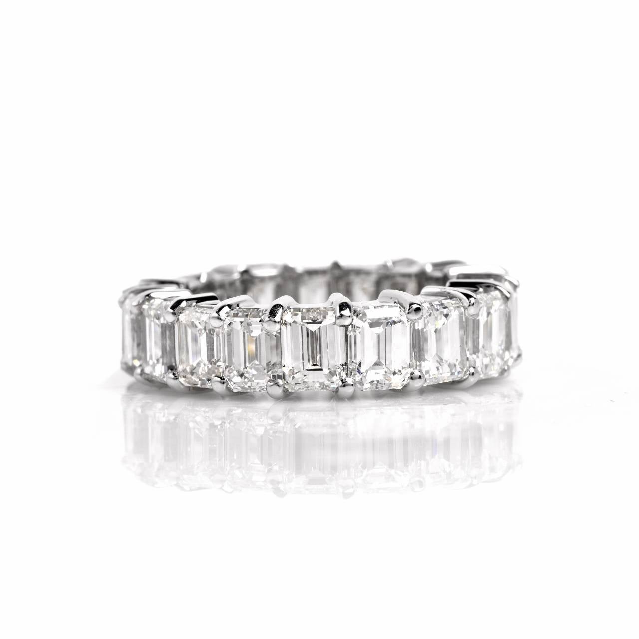 This impressive estate eternity band of opulent and sculptural tri-dimensional design is crafted in solid platinum and weighs 10.6 grams. This estate eternity band is adorned with an assemblage of 18 genuine emerald-cut  diamonds, cumulatively