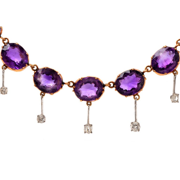 This aesthetically  breath-taking antique (Ca. 1900s) necklace resplendent in 24  evenly colored, highly translucent oval-faceted amethysts and 13 round-faceted diamonds is crafted in solid 18K yellow gold, weighs approx. 40.5 grams and measures