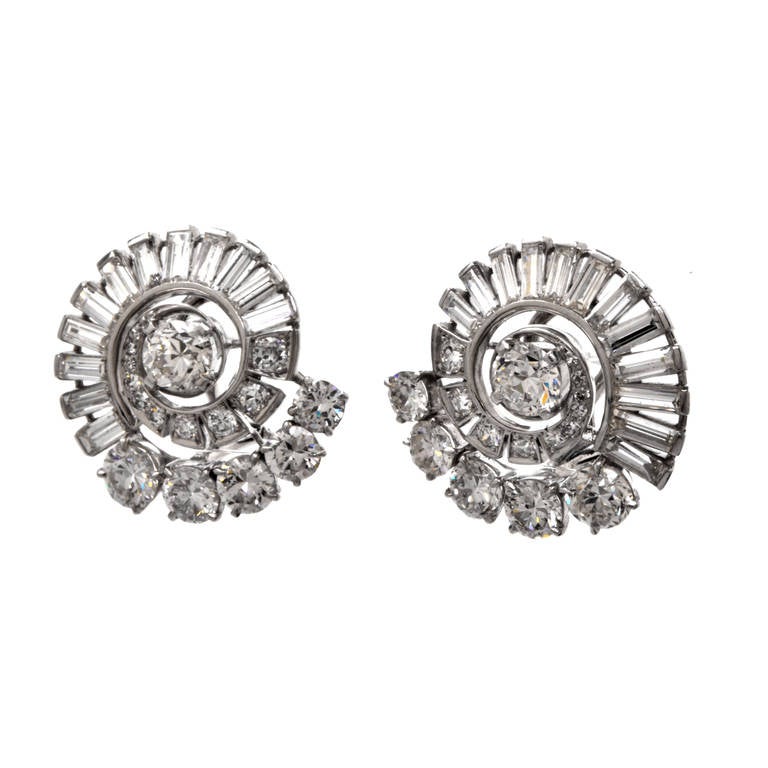These luxurious antique earrings are crafted in solid platinum. Showcasing a swirl motif, these radiant earrings are accented with 30 genuine round European cut diamonds and complemented with 24 genuine baguette cut diamonds, all approx. 5.61 cttw,