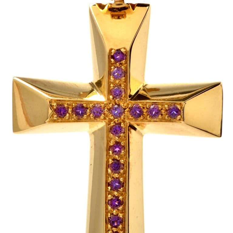 This Retro style cross pendant with round-faceted amethysts  is crafted in solid 18K yellow gold, weighing approx. 29.9 grams.  Reminiscent of the bold and sculptural designs of the Retro era, this opulent cross pendant is adorned with 24