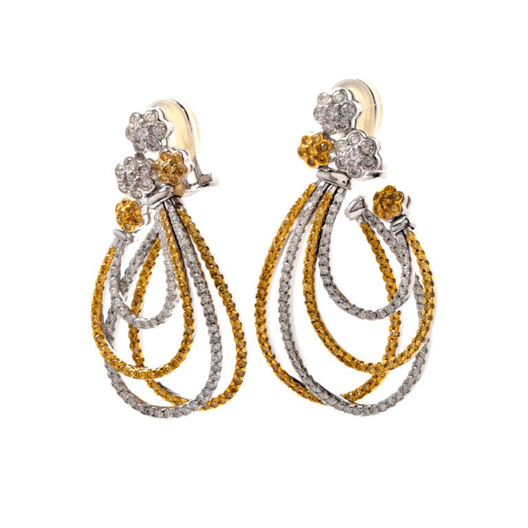 These earrings of affluent aesthetic and refined elegance are crafted in a combination of 18K white and yellow gold and weigh approx. 23.3 grams.  Incorporating  each four graduated open-end overlapping hoops of ovular format, these alluring
