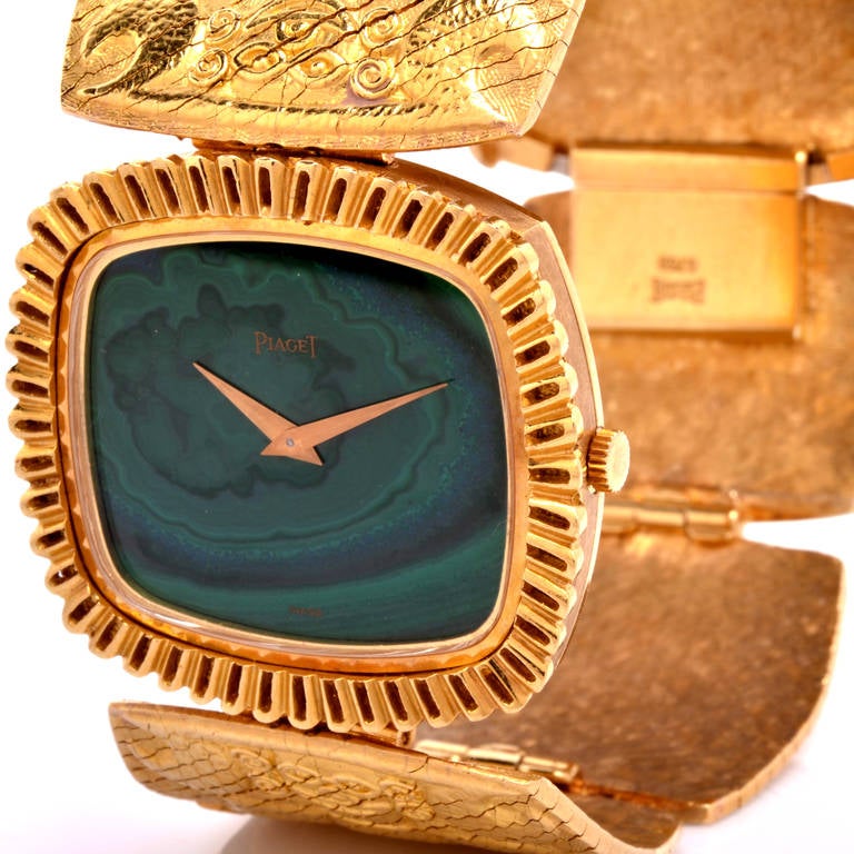 This stunning vintage Piaget watch from the 1970s is crafted in 18K yellow gold. This watch features a malachite dial with gold dauphine hands. It has a Piaget manual-wind movement. The bracelet features an intricate figure motif in a textured