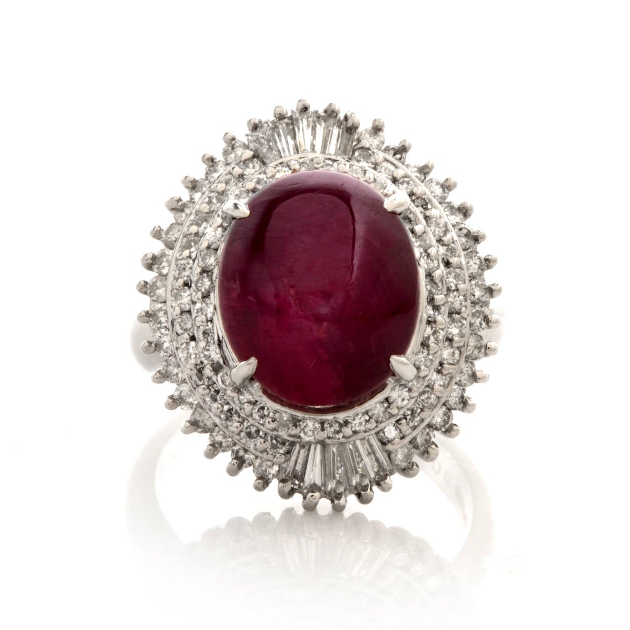 This cocktail ring with an oval cabochon star ruby, tapered baguettes and round-faceted diamonds is crafted in solid platinum and weighs 12.9 grams. Designed as a marquise-shaped plaque, this vivacious  cocktail ring is centered with a 9.08ct star