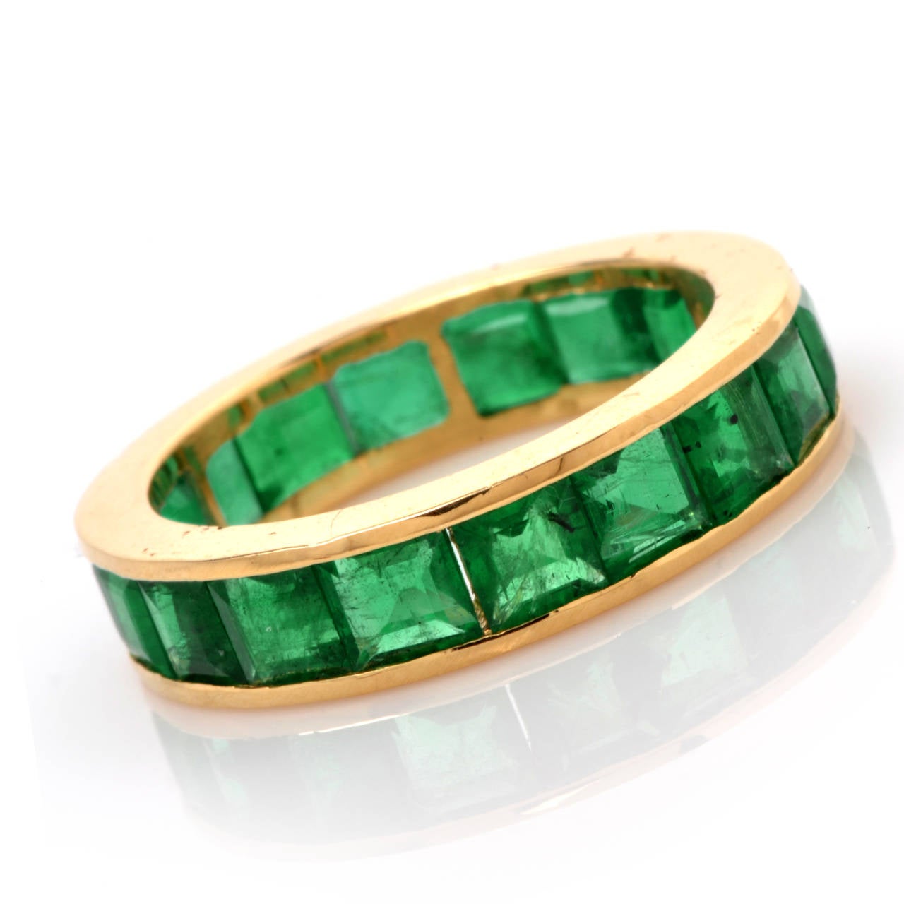 This eternity band with genuine square-cut Colombian emeralds is crafted in  solid 18K yellow gold and weighs 3.8 grams. In elegantly simple style, this vividly colored eternity band is adorned throughout with   channel-set square-cut genuine