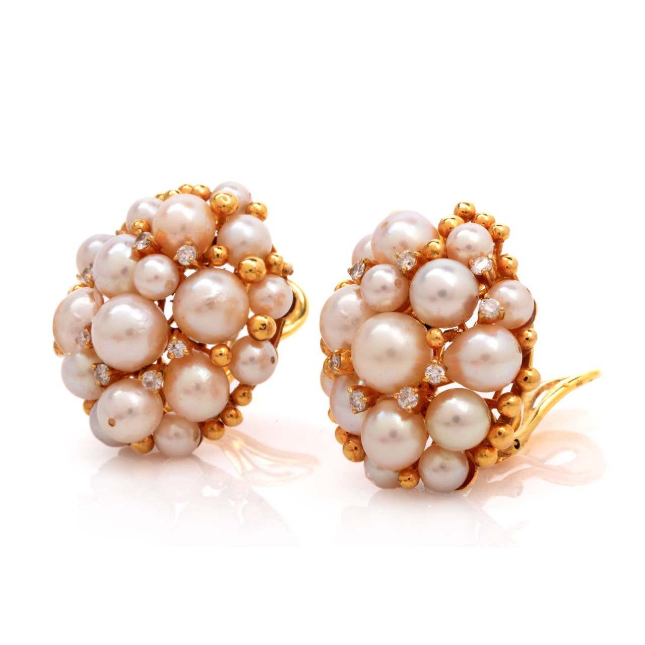 These earrings of captivating aesthetic, reminiscent of the opulent Retro earrings, are crafted in solid 18K yellow gold.  Incorporating clusters of graduated pearls mounted atop a pair of ornate, ovular plaques, these alluring earrings are adorned