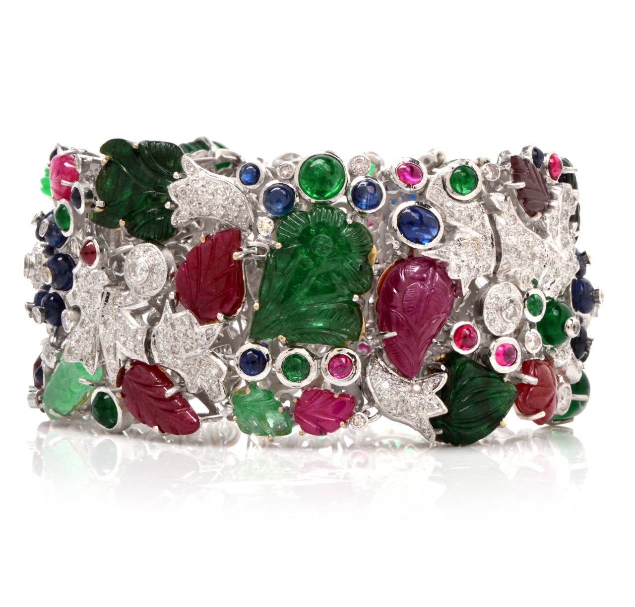 This bracelet of highly ornate, vividly colored aesthetic is crafted in solid 18K white gold. This wide, articulated strap designed bracelet in the Mogul style as a meandering vine pavé-set with round-cut diamonds, bearing a profusion of carved