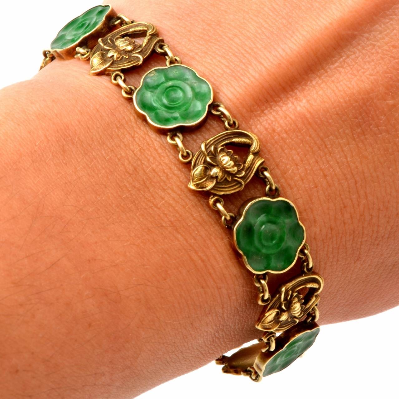 This antique Art Nouveau bracelet is crafted in 14K gold and weighs 20.00 grams and measures 7" long and 12mm wide. This naturalistically inspired bracelet of unique delicacy incorporates 6 artfully carved  jadeite flowers within gold frames of