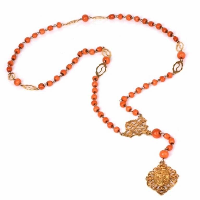 This vintage rosary with graduated ovular and round red natural coral beads is crafted in solid 18K yellow gold, weighs 35.3 grams and measures 31