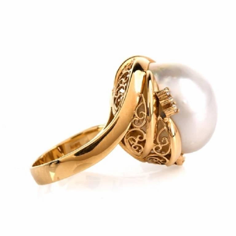 This vintage style estate cocktail ring of immaculate craftsmanship and  design is handcrafted  in solid 18K yellow gold, weighing 12.6 grams and  measuring 23 mm wide.  Incorporating a stylized ovular plaque with sensual scalloped borders, this