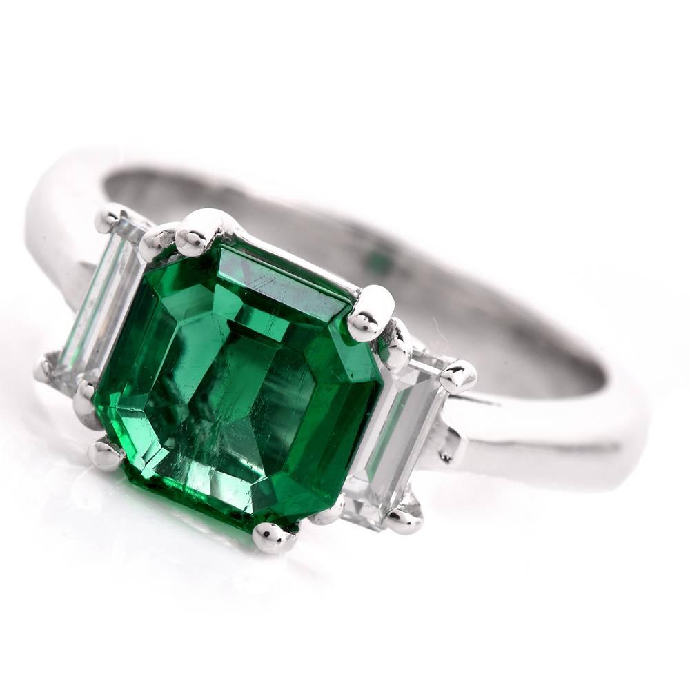 This classically distinct three-stone  ring  is  crafted in solid platinum. This exquisite ring is centered with an enchanting genuine transparent octagonal  square step-cut  Colombian emerald  of ‘intense green’ color,  approx. 1.91 carats, GIA