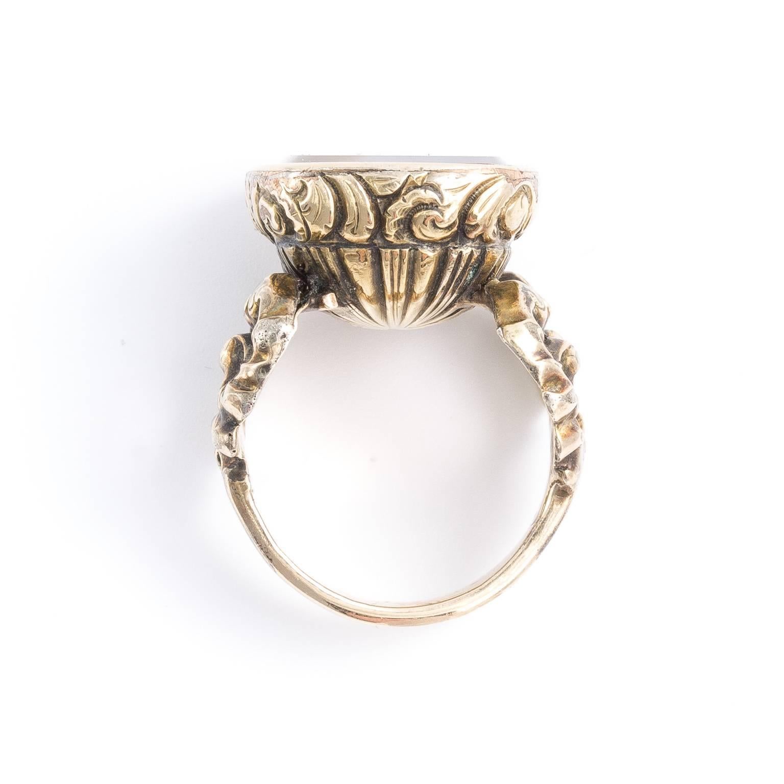 Carved quartz intaglio set into a wonderful example of mid-19th century repoussé goldwork. The ring is a size 8.25, and it weighs 23.00 grams. Intaglio Dimensions: 2.03 cm x 2.00 cm