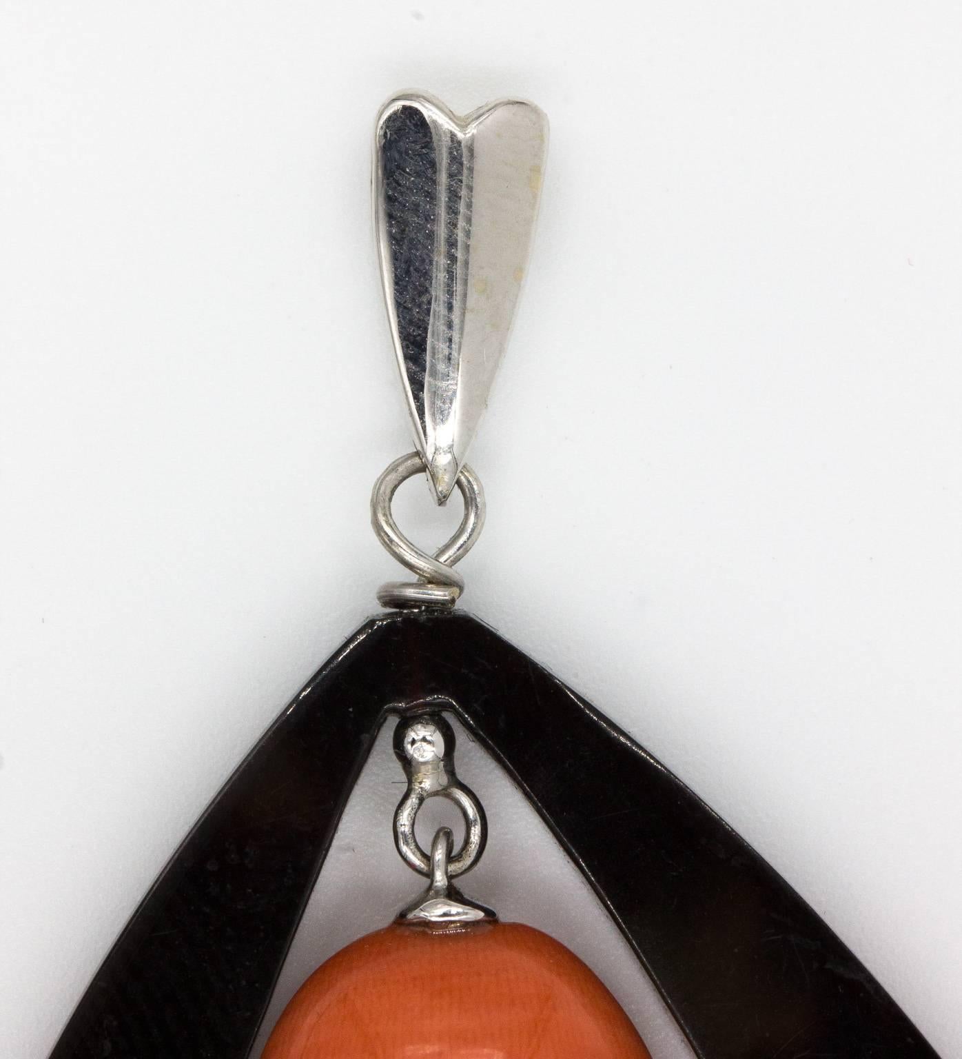 Large pendant made up of a brown Lucite frame and a suspended natural and undyed piece of coral. The coral measures 7/8 inches long and is nearly 5/8 inches wide and 7.5 mm thick. The overall pendant is 2 1/4 inches and 6.8 grams in weight. The