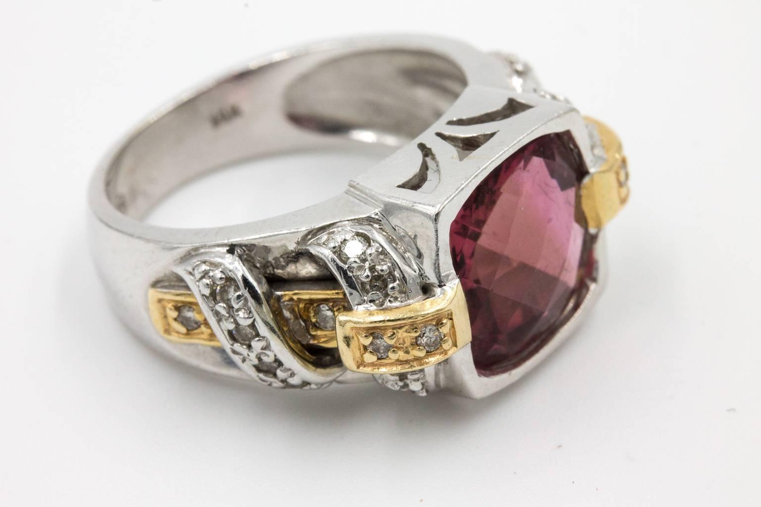 Cocktail ring with a cushion cut pink tourmaline center stone, surrounded by 24 sparkling diamonds and set in a stylish two-tone mounting. The setting is a white gold shank with yellow gold shoulders and details which are all cast in 14K gold. The