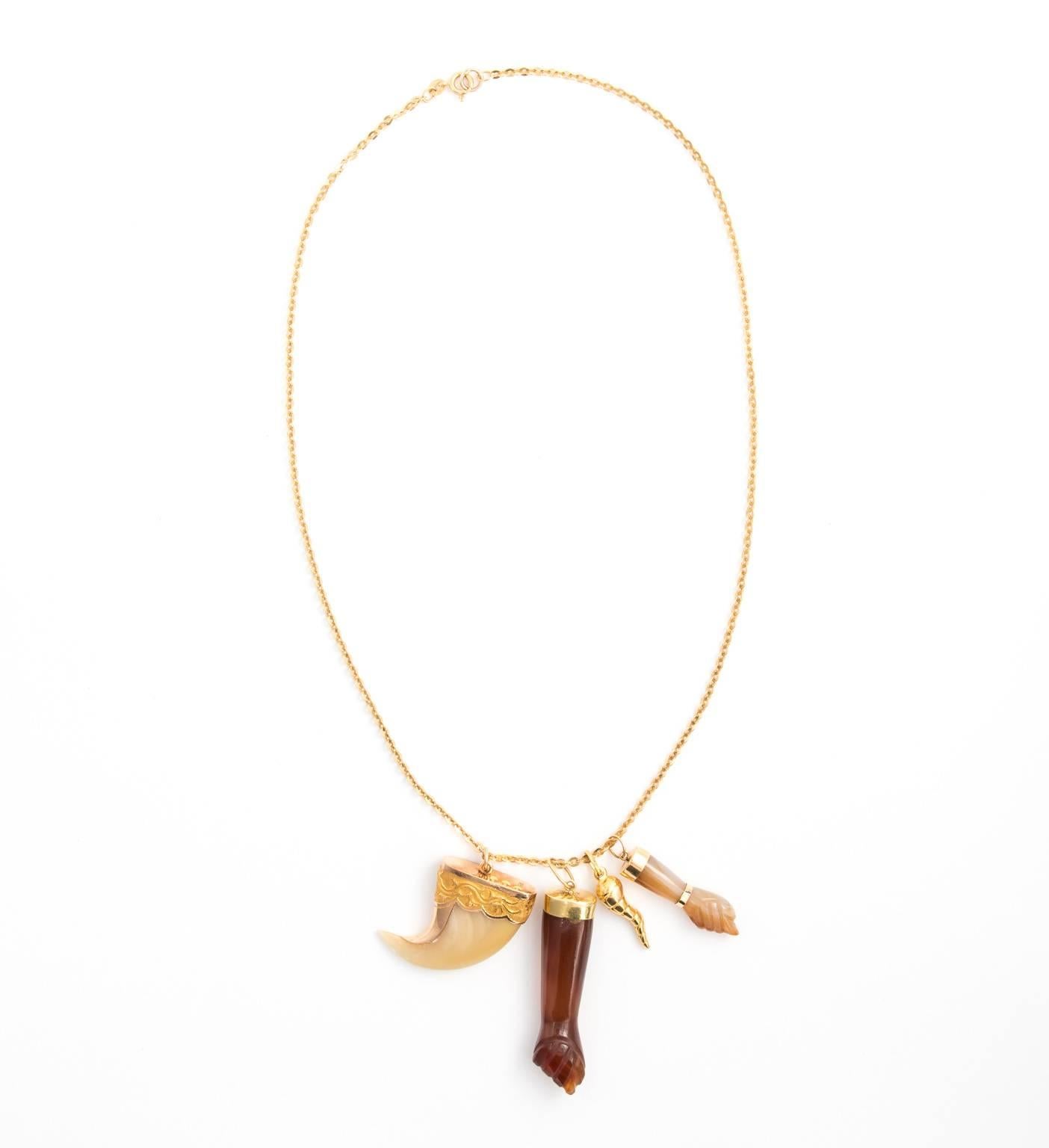 Late Victorian assemblage necklace consisting of an 18kt gold chain, agate figure charms, a whalebone pendant, and an 18kt fluted horn charm.