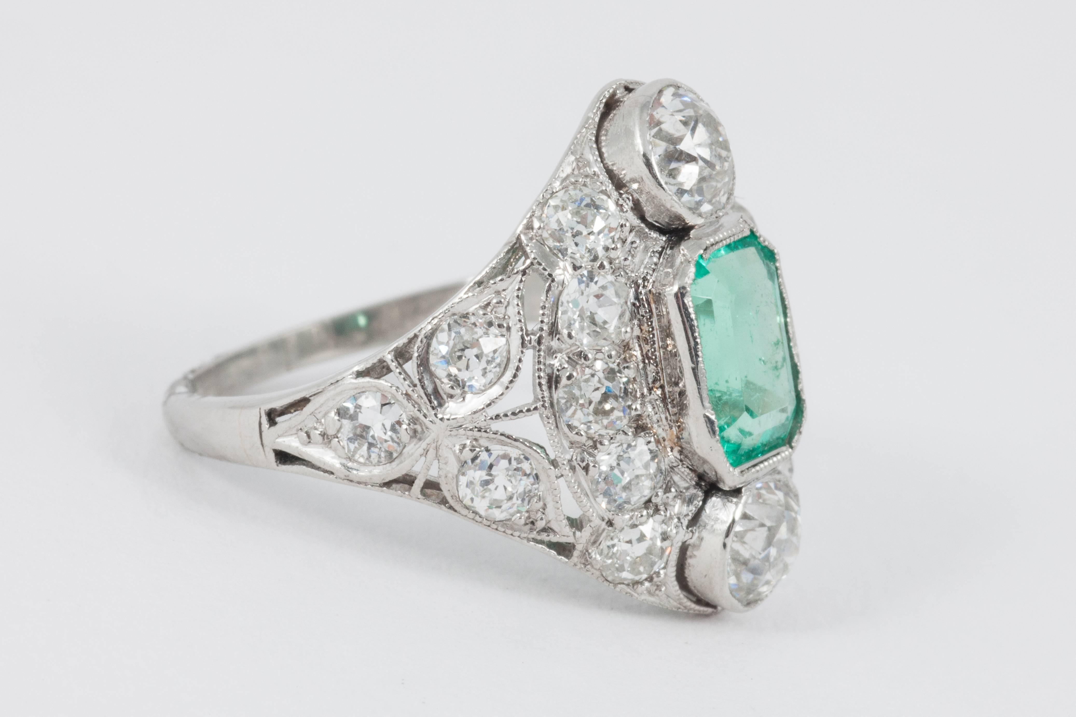 A platinum set emerald & diamond cocktail ring containing a cushion cut emerald weighing approximately 1 carat, & approximately 2.5 carat of old cut diamonds, circa 1930’s
