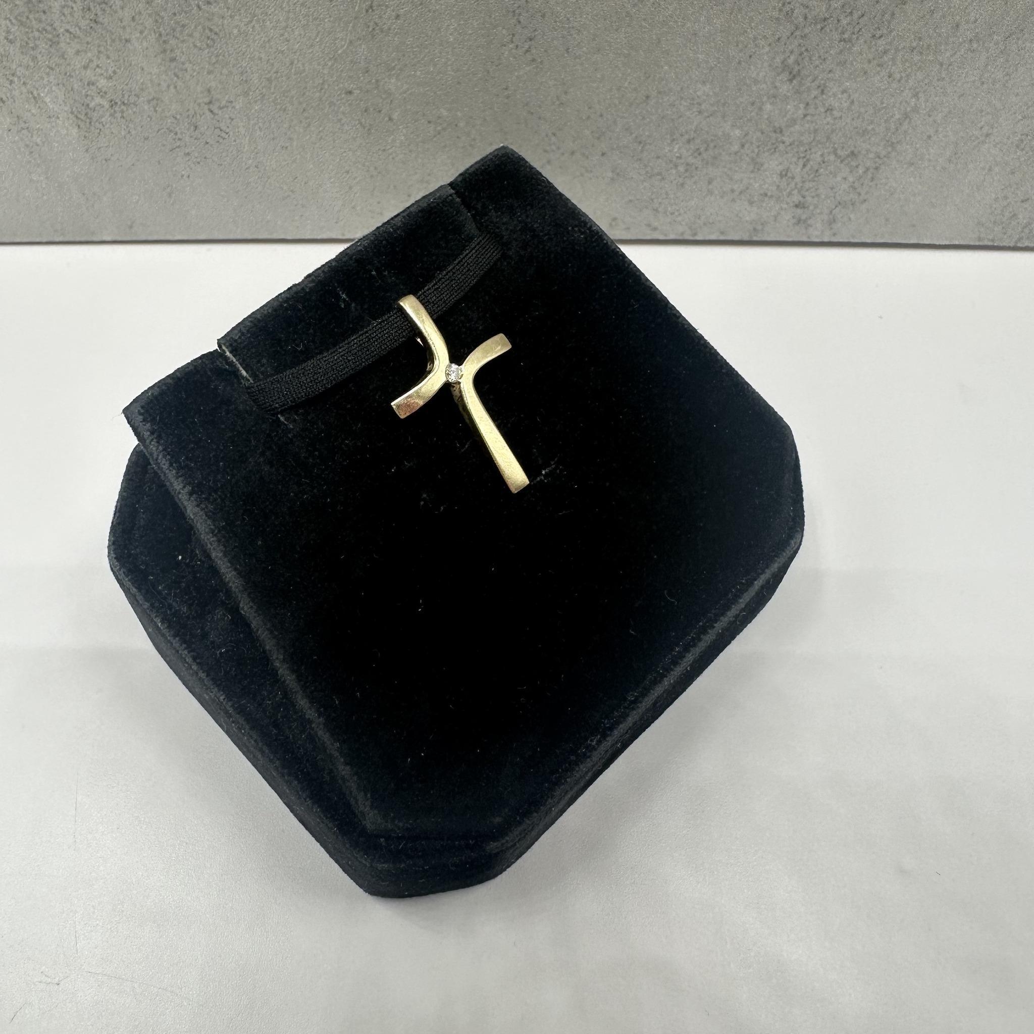 Cette croix en or jaune 14kt est ornée d'un diamant rond GH I1 de 0,02ctw, ajoutant un éclat subtil au design intemporel de la croix. Avec un poids de 1.4 grammes, il est léger et parfait pour un usage quotidien. L'attache cachée est conçue pour