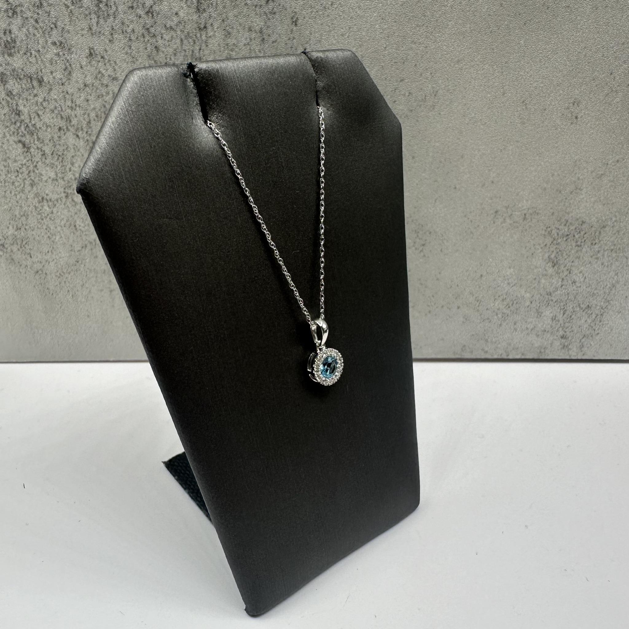 Diese elegante Topas- und Diamant-Halskette aus 10-karätigem Weißgold besteht aus einem 4 mm großen, runden Schweizer Blautopas, der von 0,06 ct natürlichen, runden Diamanten im Einzelschliff (GH I1) akzentuiert wird, die ihm einen Hauch von Glanz