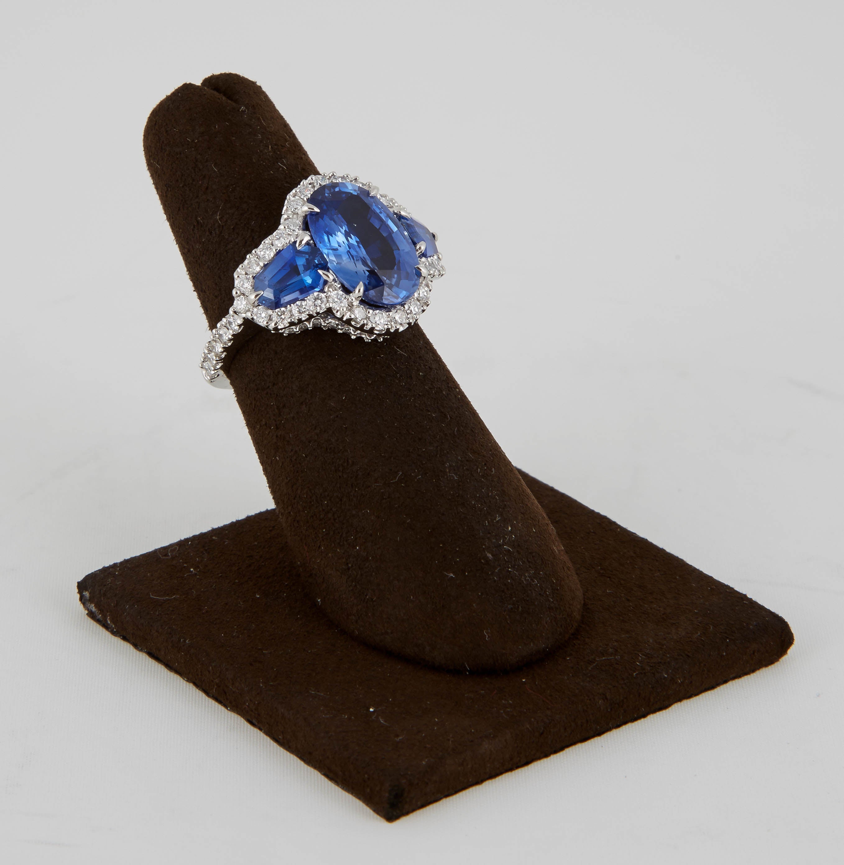 

A stunning and unique ring to add to any collection.

A beautiful 5.10 carat center oval sapphire is set with rare special cut sapphire side stones weighing 1.43 carats for a total of 6.53 carats of fine blue sapphire.

The stones are surrounded