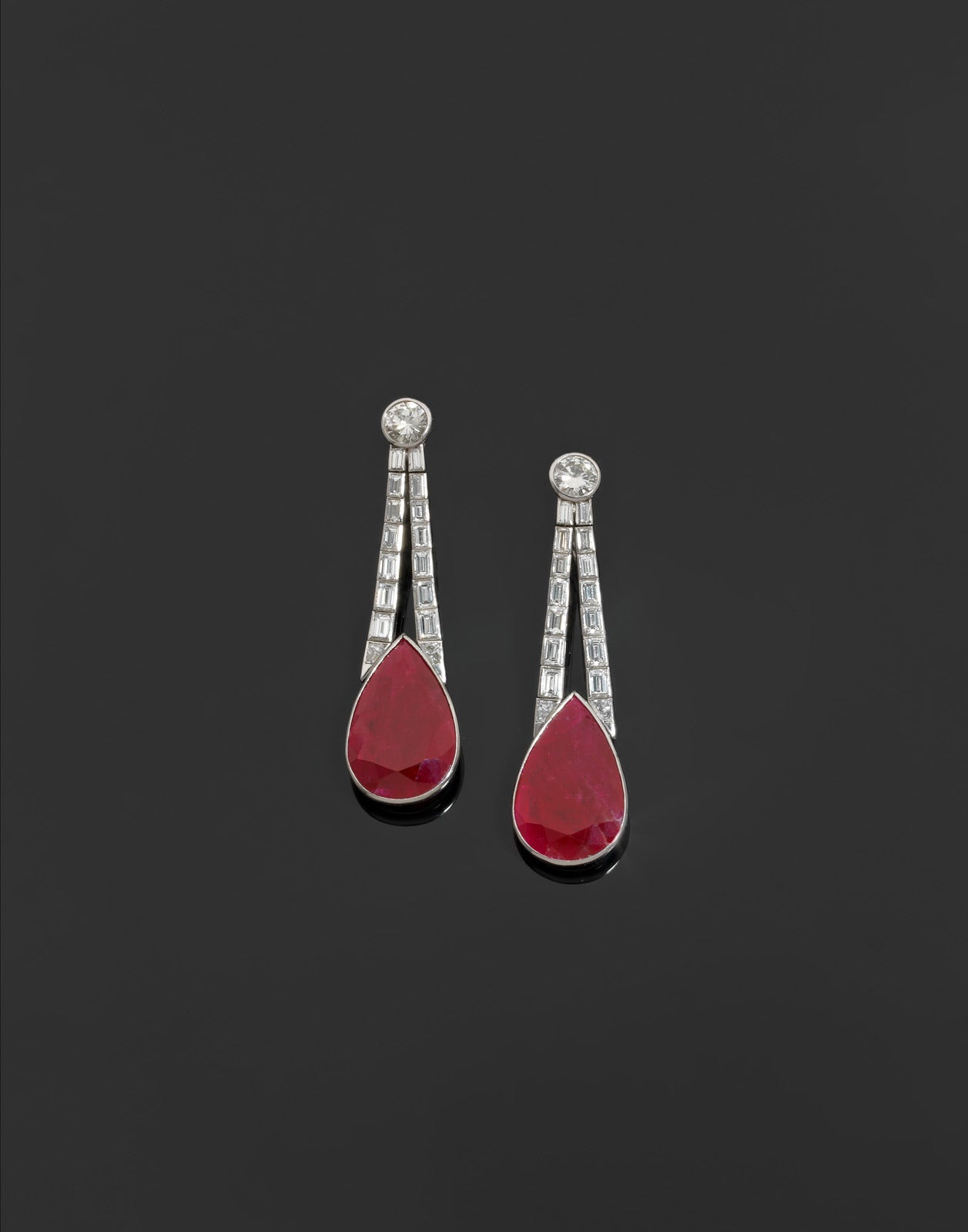 Pair of ear pendants holding a pear-cut ruby of about 14 carats each, platinum mount of two rows of articulated rectangular links set with emerald cut diamonds and a round brilliant cut diamond weighing approx. 3.75 carats, IGM certificate stating