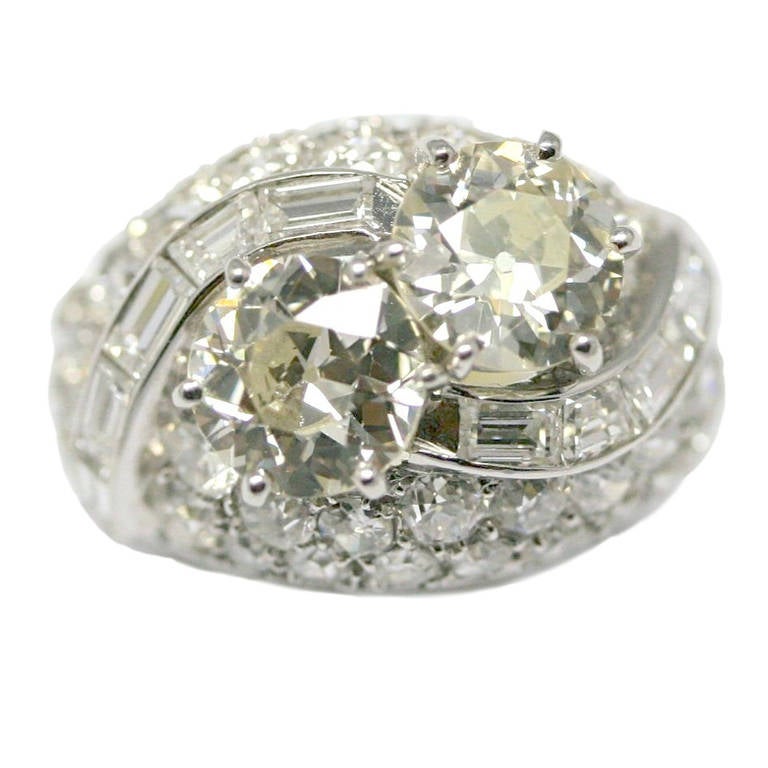 1930 Dome ring set with two round cut diamonds of approximately 1.5 and 1.6 carat, platinum setting paved with baguette-cut diamonds, ring size 6.5 (10,9grs)