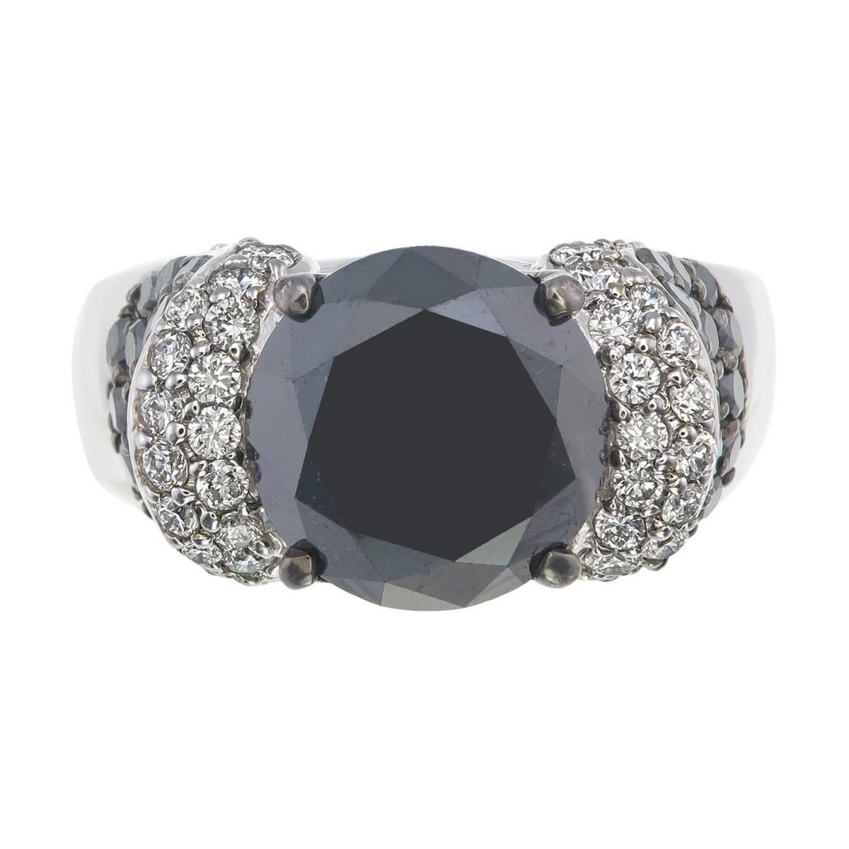 Im Mittelpunkt dieses auffälligen Rings steht ein runder schwarzer Diamant von 6,62 Karat - ein dramatischer und fesselnder Edelstein, der durch seine Tiefe und sein Geheimnis Aufmerksamkeit erregt.

Das Besondere an diesem Stück ist die Art und