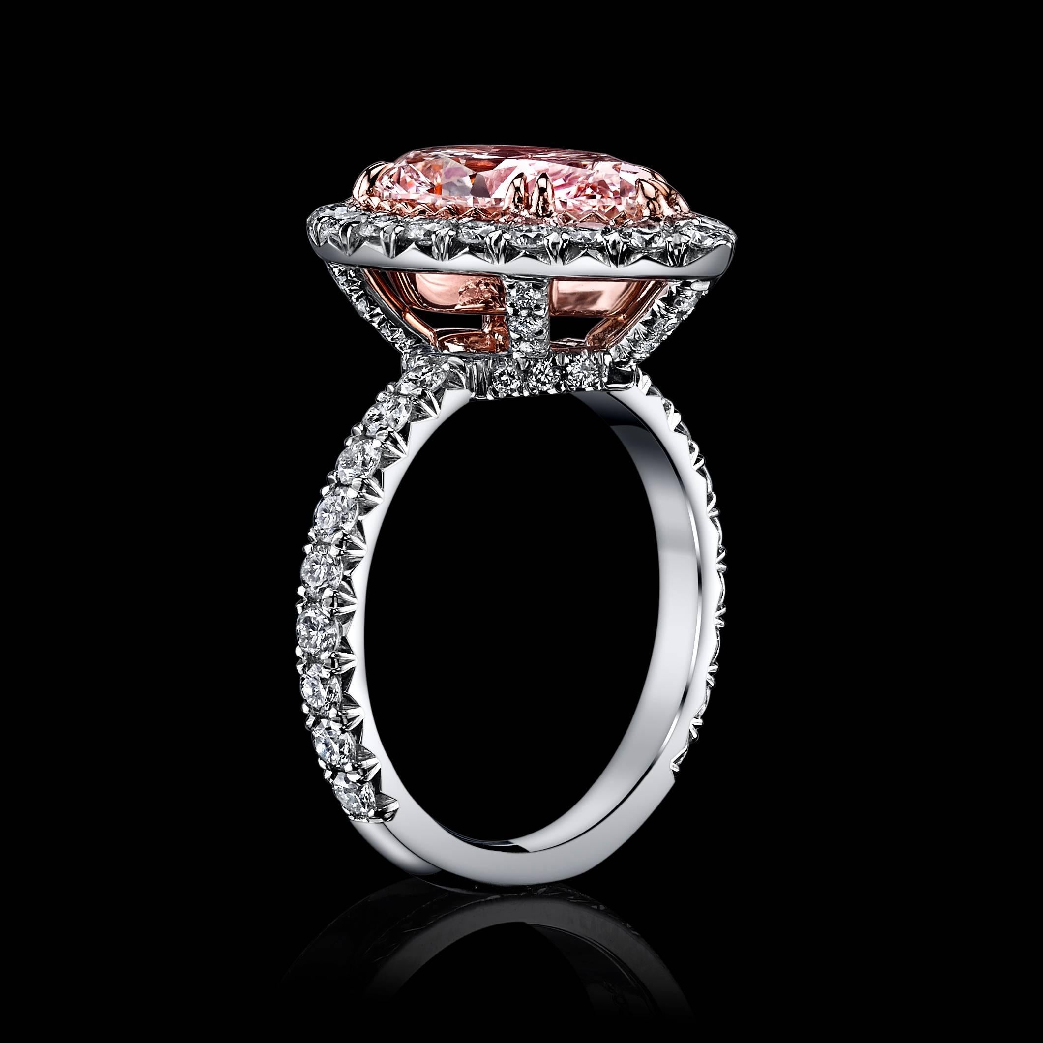 A stunning, 1.72ct GIA Certified Fancy Light Pink diamond, surrounded by a halo of round brilliant colorless diamonds, mounted in Platinum & 18K Rose Gold. An additional 57 round diamonds set into the halo and mounting, add a carat weight of 1.23 to