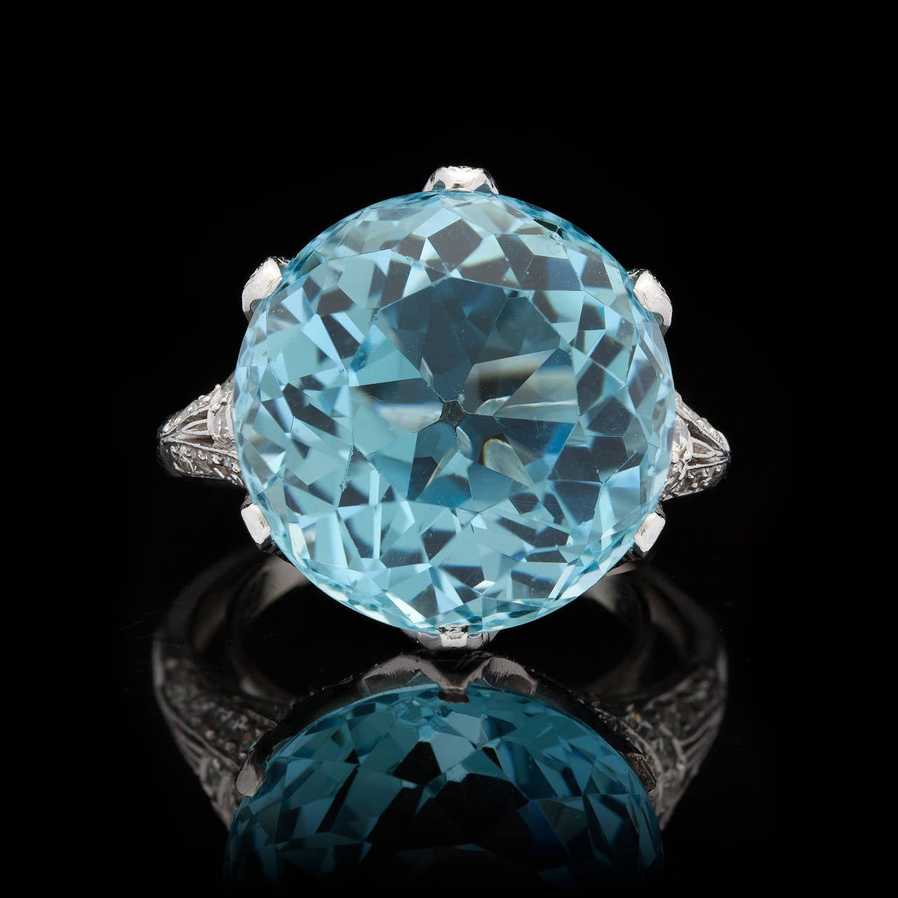 Ring Features One 12.00ct Round Cut Aquamarine Set in a 14Kt White Gold Woven Back Mounting Adorned with 70 Round Cut Diamonds, with a total approximate diamond weight of 1.10cts. The ring is a size 7.75 and weighs 9.5 grams.