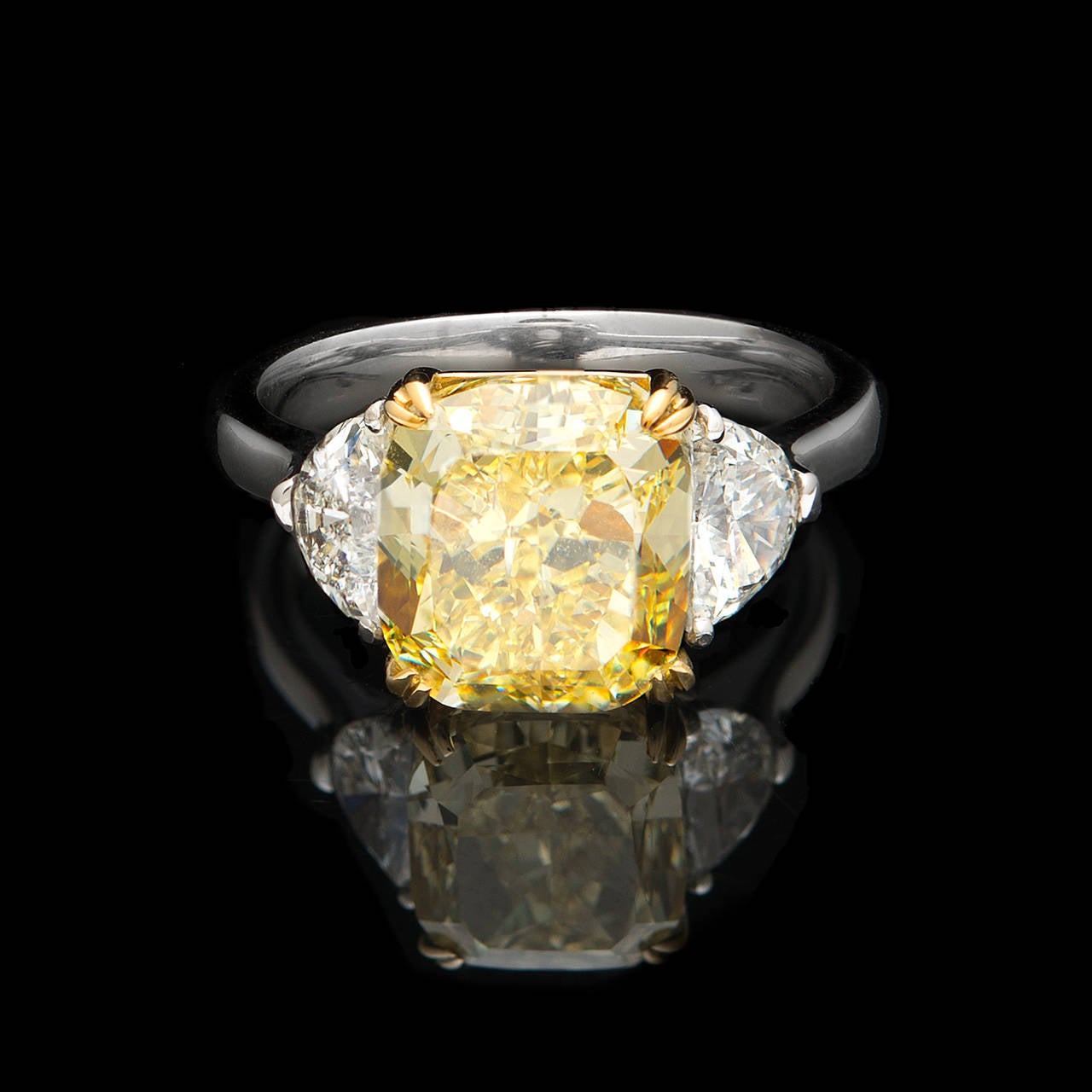 GIA Natural Fancy Intense Yellow Diamond weighing 5.01cts set in Platinum accented by four 18Kt Yellow Gold Double Prongs. The color is evenly distributed through this breathtaking Rectangular Round-Cornered Modified Brilliant Cut VVS1 Diamond and