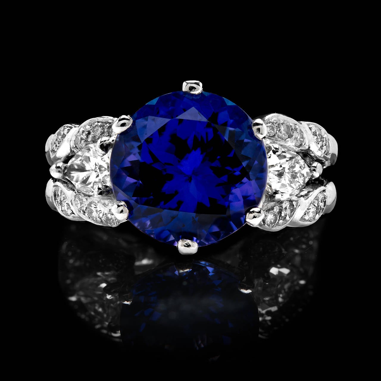 Platinum Ring Features a Vibrant Purplish Blue 5.25 Carat Tanzanite Flanked by 1.00 Carat of Pear Shaped and Round Cut Diamonds. The ring measures 12mm to 4mm and is a size 7.0. Total weight is 13.4 grams.